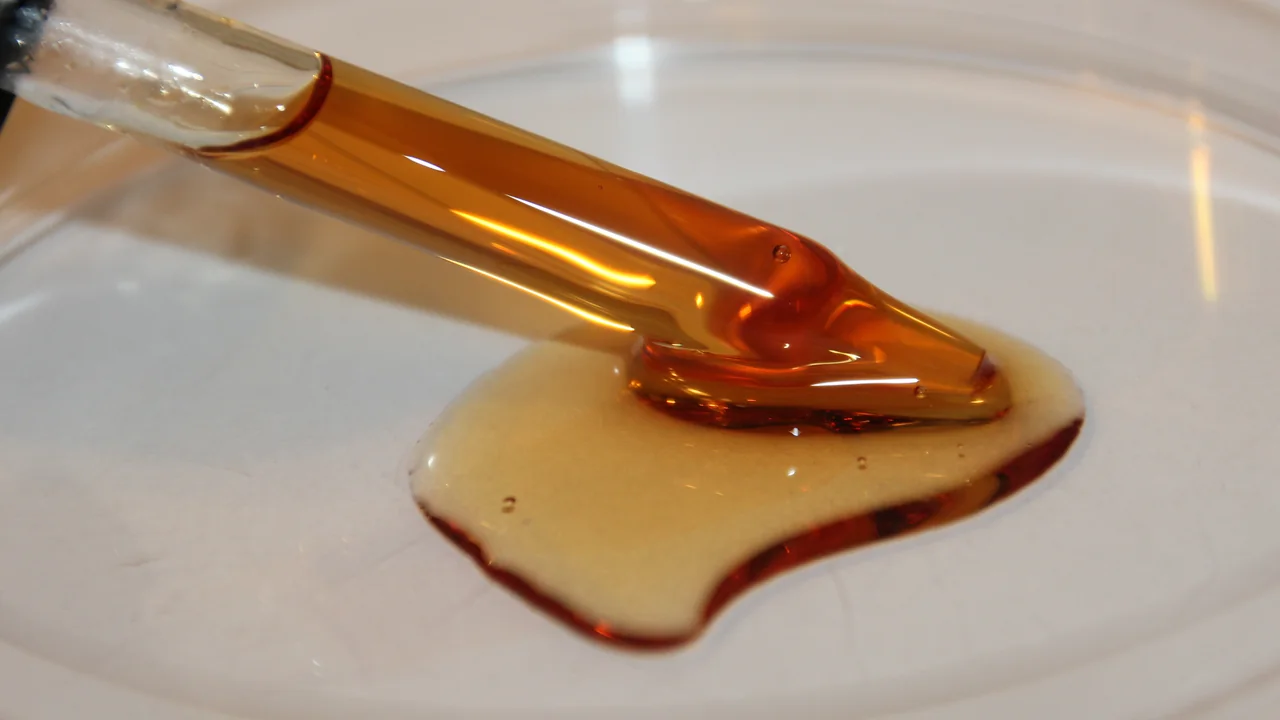 Imagem ilustrativa de um sérum oleoso com vitamina E e creme cosmético em uma placa branca