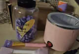 Aquecedor, pote de cera e espátulas usados como ilustração de materiais para depilação