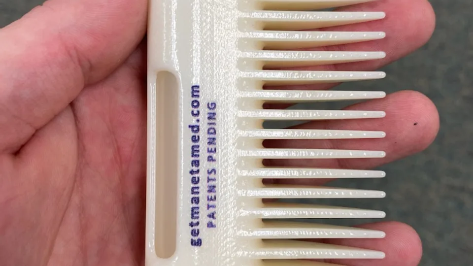 Pente para barba mostrado na mão, visto pelo verso