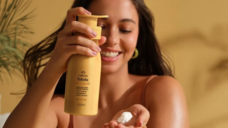 Pessoa aplicando produto corporal nas mãos durante uma rotina de cuidados