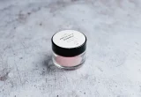 Pote de cosmético fotografado sobre uma superfície clara, usado como imagem destacada de artigo sobre leitura de ingredientes e rótulos.