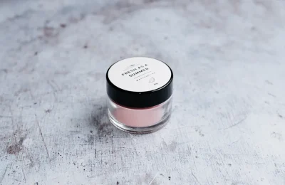 Pote de cosmético fotografado sobre uma superfície clara, usado como imagem destacada de artigo sobre leitura de ingredientes e rótulos.