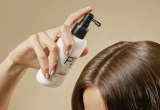 Mão aplicando produto capilar com válvula pump sobre os cabelos