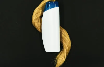 Frasco de produto capilar sem marca sobre uma mecha de cabelo, representando um finalizador leave-in.