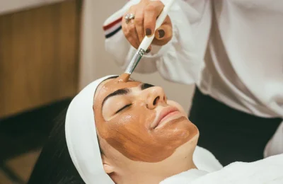 Profissional aplica máscara de skincare no rosto de uma mulher