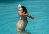Mulher dentro de uma piscina tocando o cabelo molhado