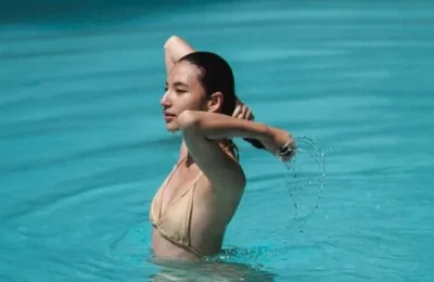 Mulher dentro de uma piscina tocando o cabelo molhado
