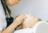 Profissional aplicando produto próximo aos cílios de uma cliente