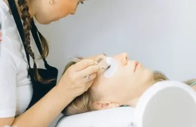 Profissional aplicando produto próximo aos cílios de uma cliente