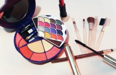 Produtos de maquiagem, incluindo lápis cosméticos e pincéis, sobre uma superfície clara.