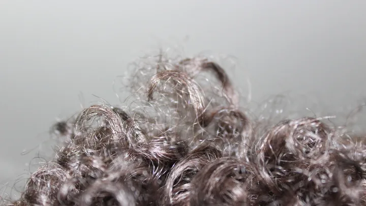 Textura de cabelo cacheado em close para ilustrar a escolha de mousse capilar.
