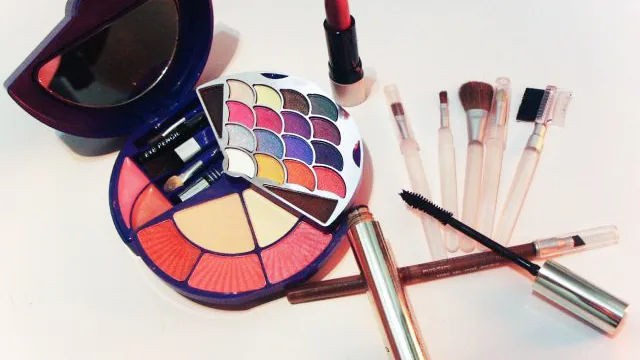 Paleta de maquiagem, batom e pincéis em fotografia ilustrativa sobre leitura de rótulos de cosméticos.