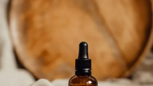 Frasco conta-gotas de sérum capilar sobre uma superfície de madeira