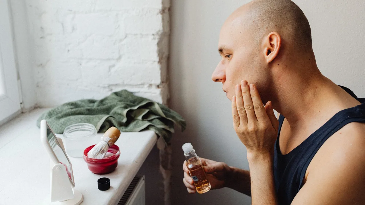 Homem aplica um produto cosmético no rosto durante uma rotina facial