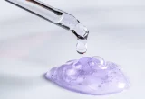 Pipeta libera uma gota de sérum sobre um gel em laboratório cosmético