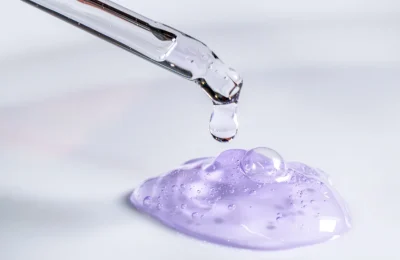 Pipeta libera uma gota de sérum sobre um gel em laboratório cosmético