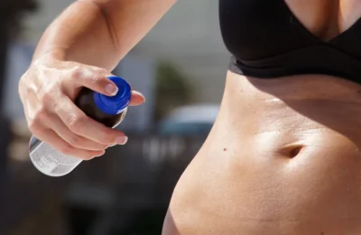 Pessoa aplicando protetor solar em spray no corpo