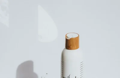 Frasco de cosmético branco sobre superfície clara, imagem ilustrativa para guia de cosméticos sem fragrância