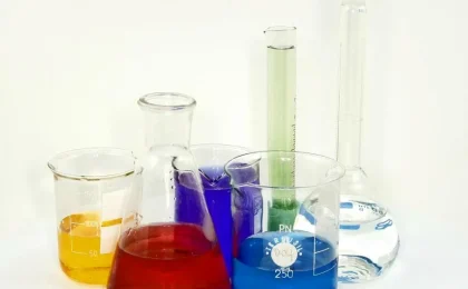 Vidrarias de laboratório com soluções coloridas, imagem contextual sobre pesquisa de ingredientes cosméticos.
