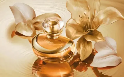 Frasco dourado do perfume Lily L’Or Elixir entre flores de lírio