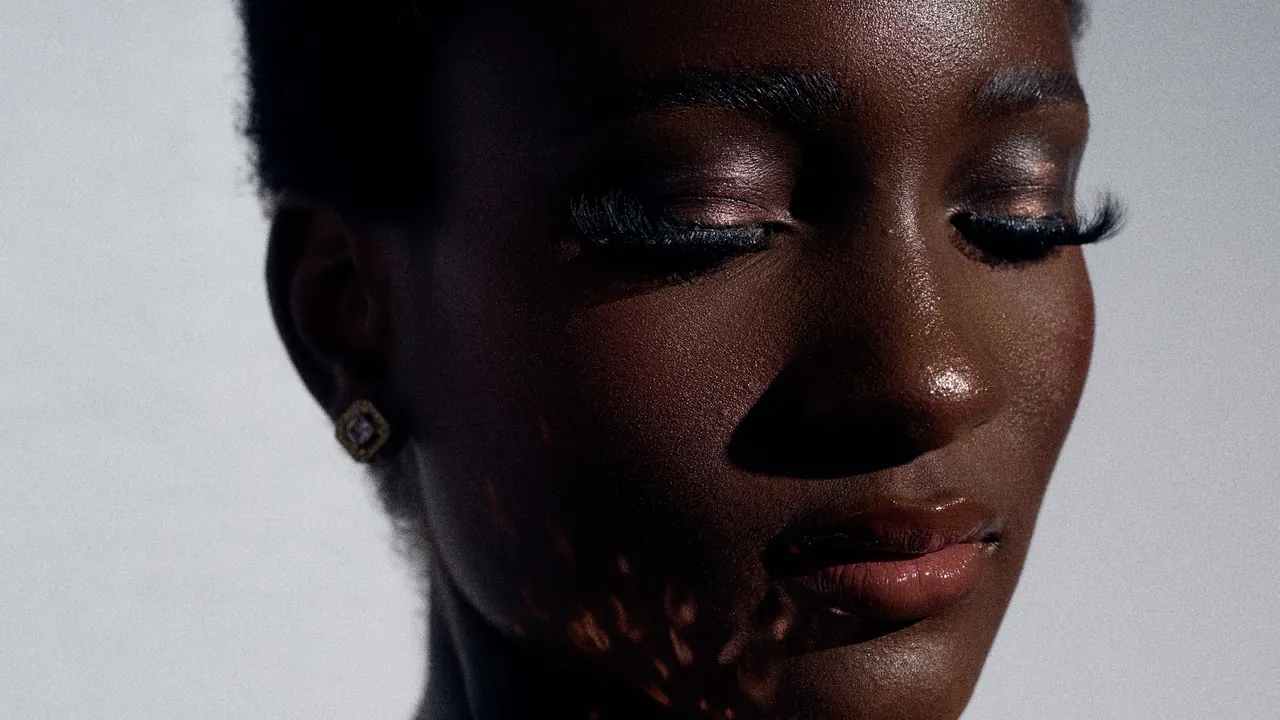 Close de mulher negra usando maquiagem nos olhos e no rosto
