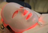 Máscara LED facial com luz vermelha em procedimento de skincare.