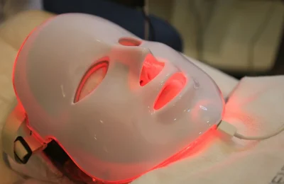 Máscara LED facial com luz vermelha em procedimento de skincare.