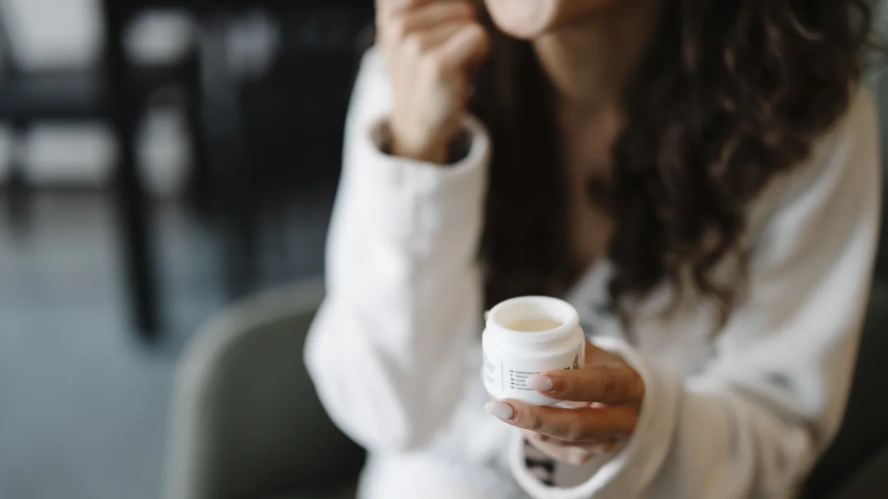 Pessoa aplicando creme no rosto em casa, imagem contextual sobre o uso de cosméticos