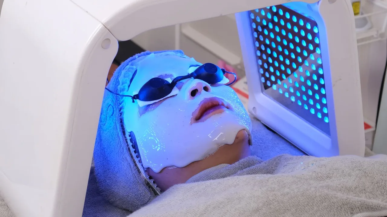 Procedimento facial com luz azul e proteção ocular.