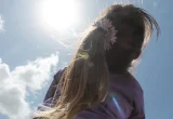 Pessoa com cabelo preso ao ar livre, sob luz solar direta, ilustrando a exposição dos fios aos raios UV
