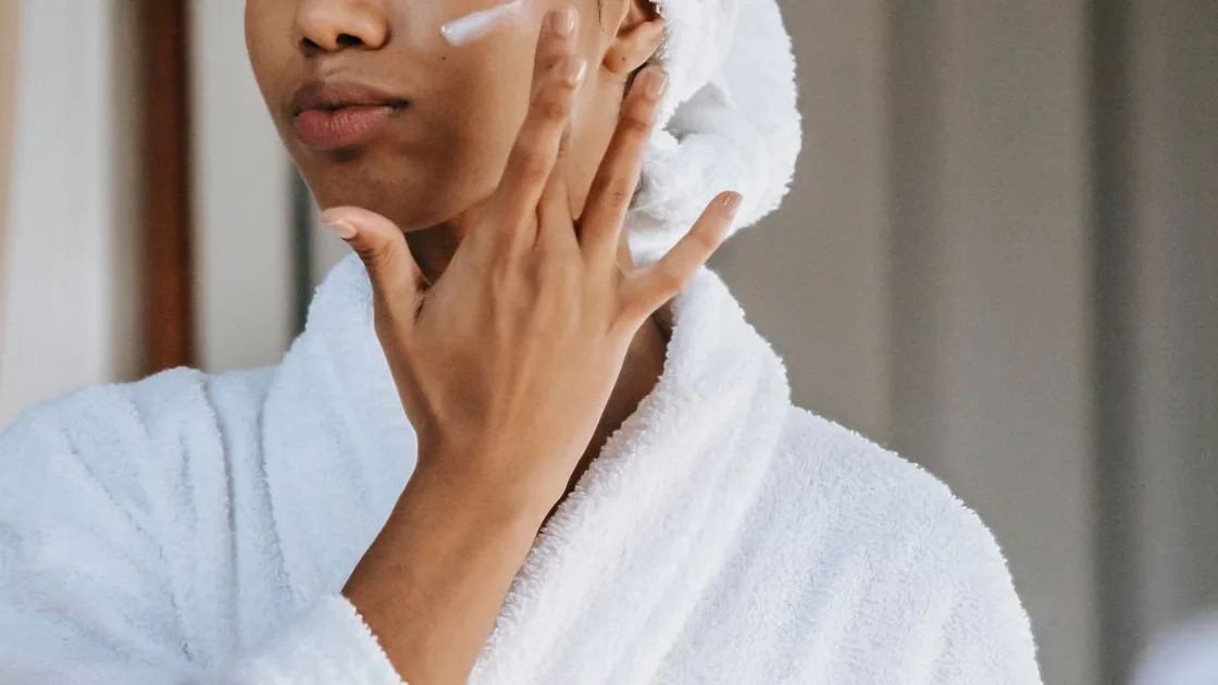 Pessoa aplica creme facial na bochecha durante uma rotina de cuidados com a pele