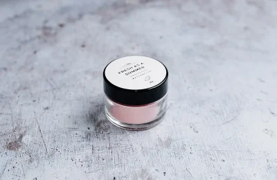 Pote de cosmético com creme rosado sobre uma superfície clara