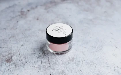 Pote de cosmético com creme rosado sobre uma superfície clara
